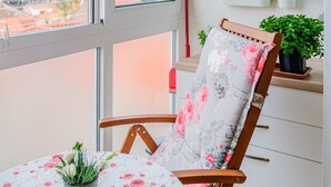 A balcony with a wooden chair, a table with a floral tablecloth, and potted plants on shelves. - Apartment City Walk (Split)