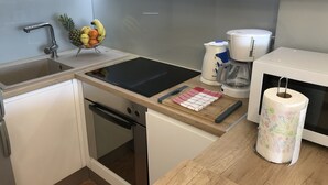 A modern kitchen with a stainless steel sink, a fruit bowl, a coffee maker, and a microwave. - Apartment City Walk (Split)