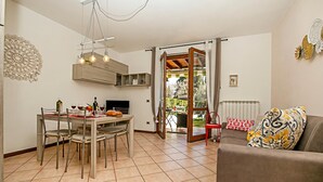 A dining area with a table and chairs, a sofa, and a view through an open door to an outdoor space. - Borgo Degli Ulivi shared pool- 200m lake (Toscolano Maderno)