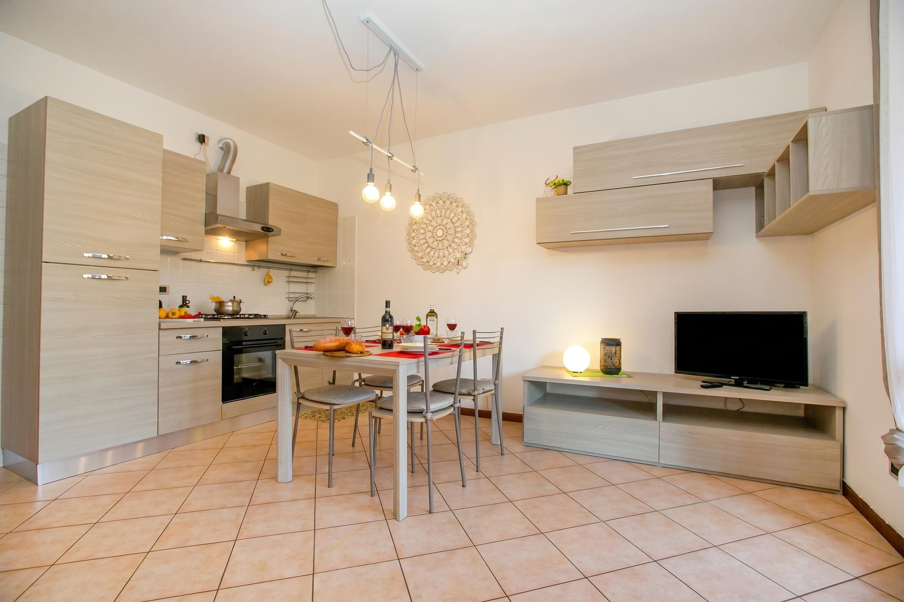A modern kitchen with a dining area, built-in appliances, and a flat-screen TV.
