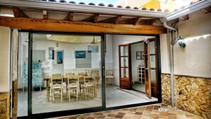 Une terrasse couverte avec une porte-fenêtre coulissante donnant sur un coin repas équipé d’une table et de chaises.