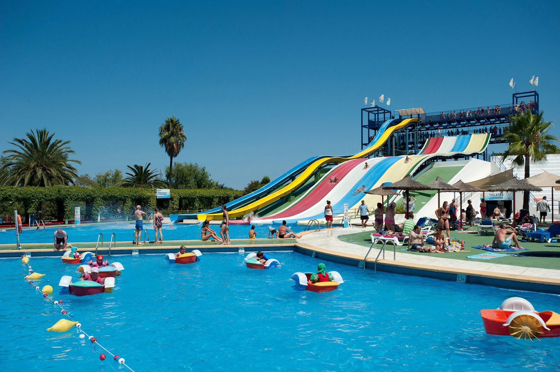 A swimming pool with a water slide and inflatable boats.