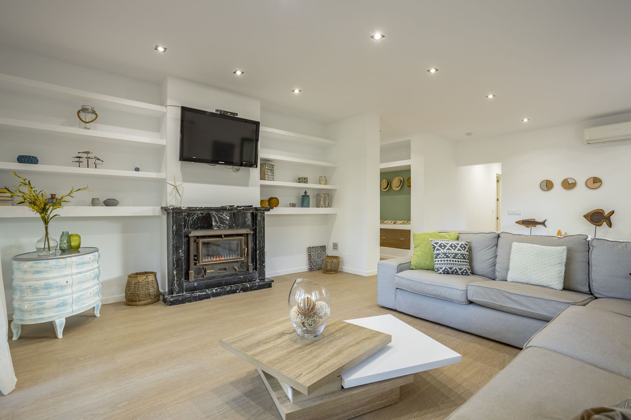 Ein modernes Wohnzimmer mit Kamin, Flachbildfernseher und grauem Sofa.