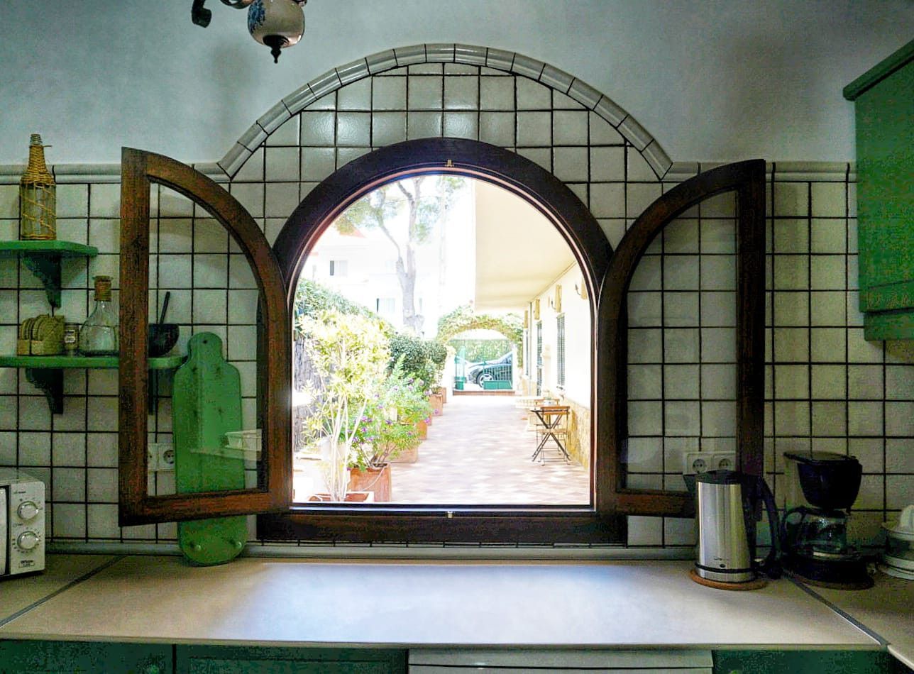 Una cocina con un ventanal amplio, una cafetera y un estante verde.