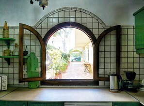 A kitchen with a large window, a coffee maker, and a green shelf. - Modern house with 3 bedrooms, 2 bathrooms, wifi, terrace and barbecue 100 meters from the beach (Puerto de Alcudia)