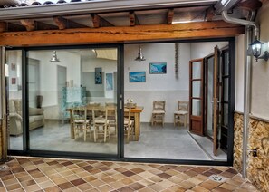 Un coin repas doté d’une porte coulissante en verre, de chaises en bois, d’une table et offrant une vue sur l’intérieur.