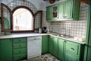 A kitchen with green cabinets, a white dishwasher, a sink, and a window with a view of the outside. - Modern house with 3 bedrooms, 2 bathrooms, wifi, terrace and barbecue 100 meters from the beach (Puerto de Alcudia)
