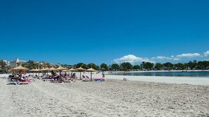 Une plage avec des transats et des parasols, un ciel dégagé et une mer calme.