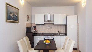 Une cuisine de taille réduite avec des meubles blancs, une cuisinière et une table à manger avec des chaises.