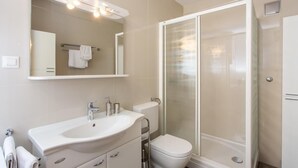 Une salle de bain moderne avec un lavabo blanc, un miroir et des toilettes.