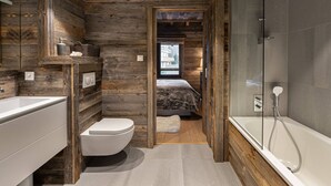 A bathroom with a wooden interior, a white toilet, a sink, and a glass-enclosed shower. - Modern duplex near slopes with parking (Méribel)