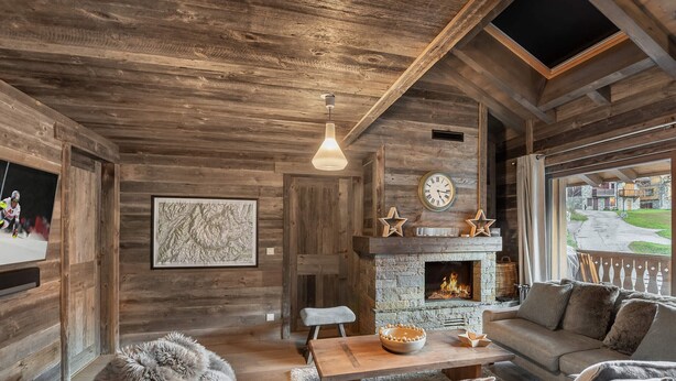 A rustic cabin interior with a stone fireplace, wooden walls, a cozy seating area, and a television on the left wall. - Modern duplex near slopes with parking (Méribel)