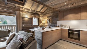 A modern kitchen with wooden cabinetry, a central island, and a dining area with a sofa. - Modern duplex near slopes with parking (Méribel)