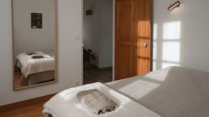 Un dormitorio con una cama grande, una puerta de madera, un espejo y una lámpara fijada a la pared.