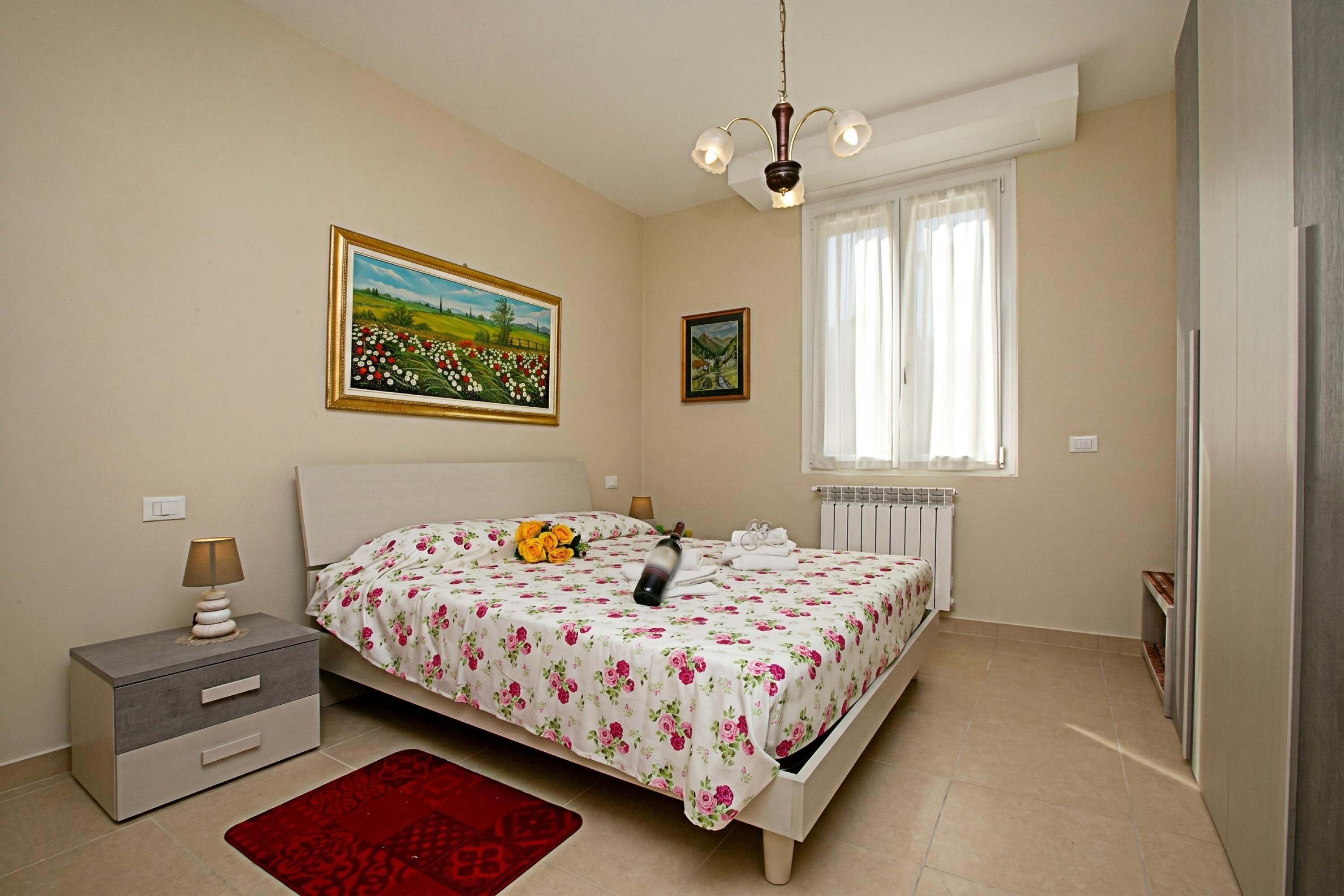 A bedroom with a bed, nightstand, lamp, and a window with curtains.