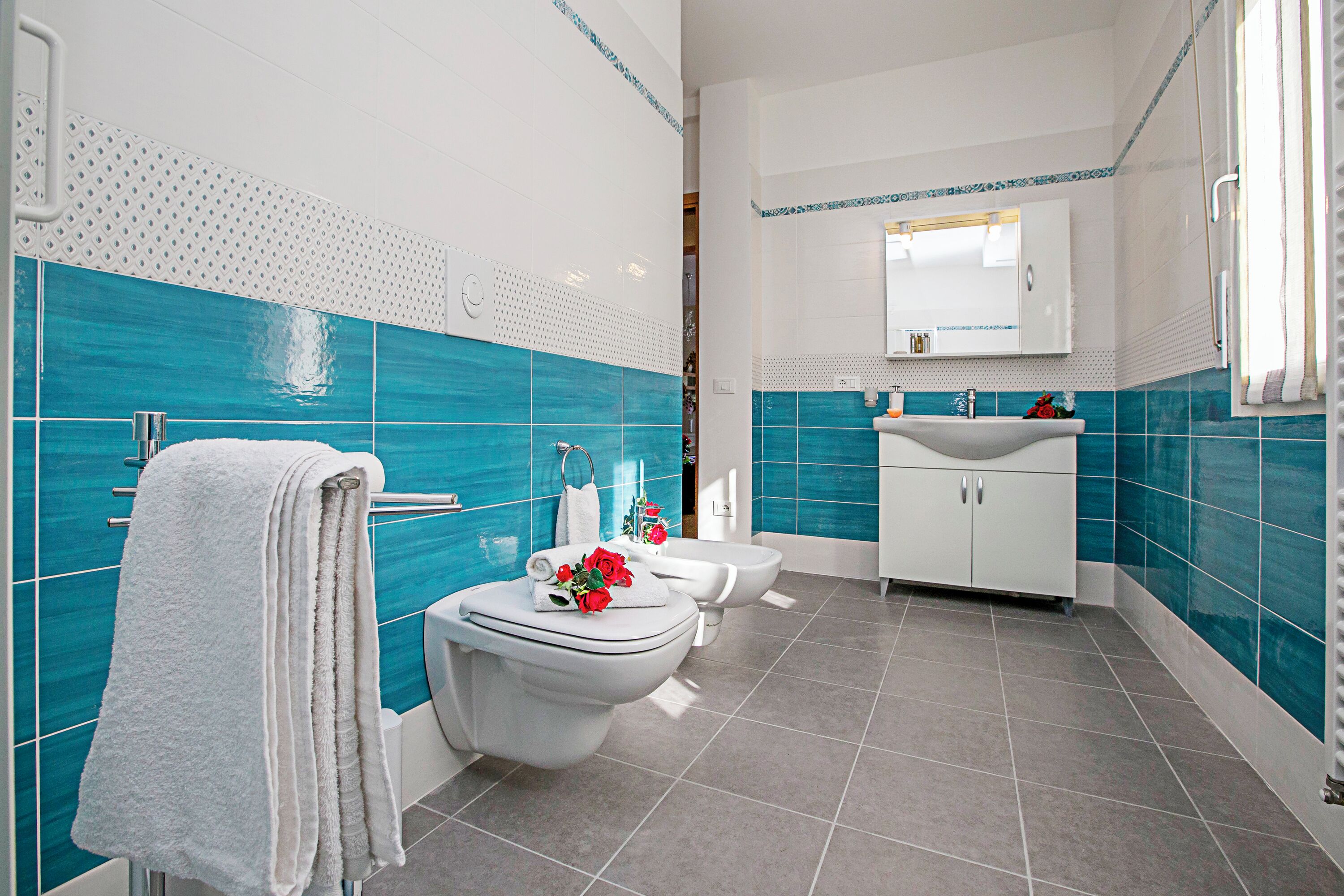 Ein modernes Badezimmer mit zwei Toiletten, einem Waschbecken und einem Spiegel darüber.