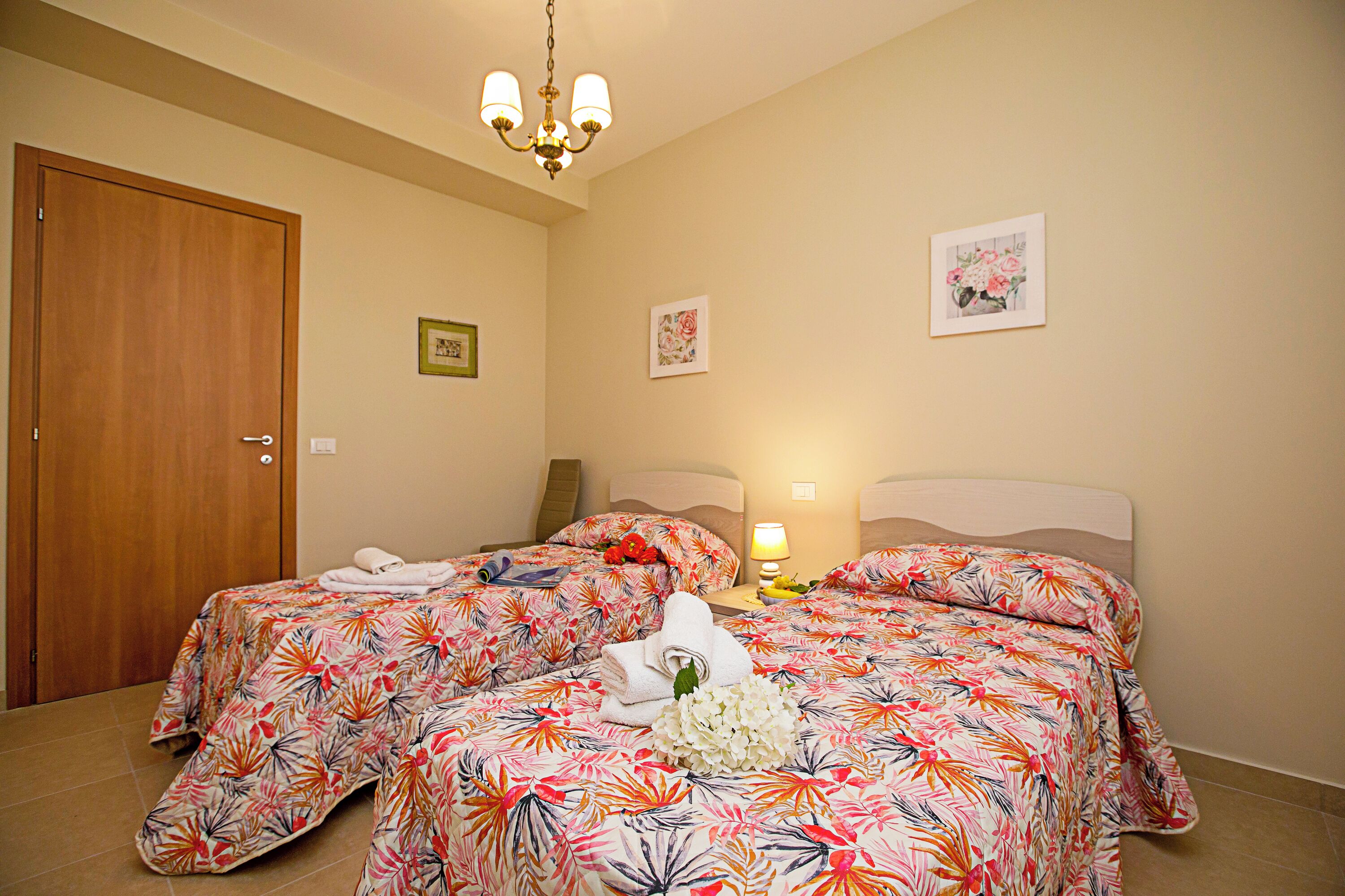 A hotel room with two beds, a chandelier, and artwork on the walls.