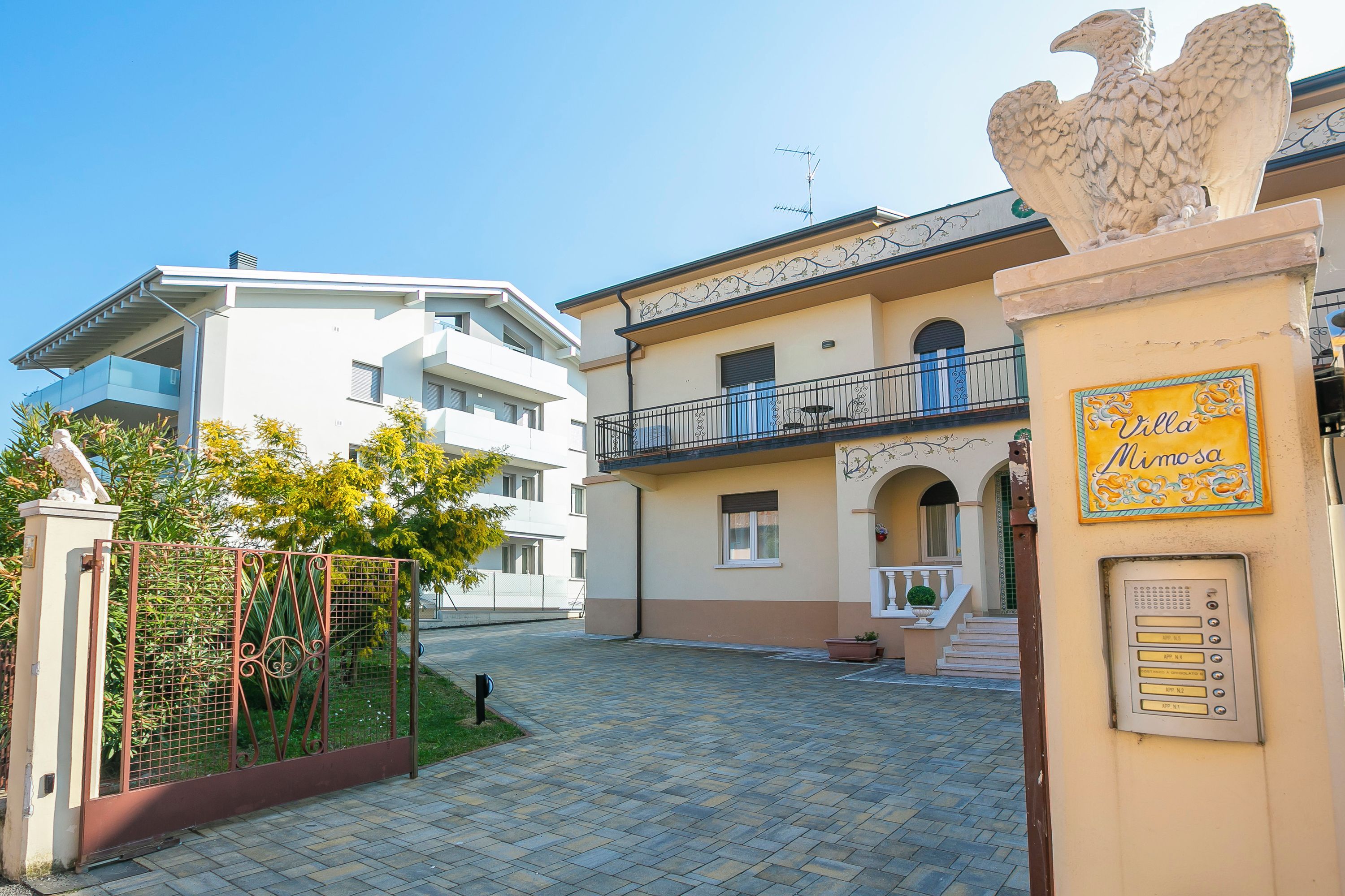 A gated courtyard with a building featuring a balcony and a plaque reading "Villa Mimosa."