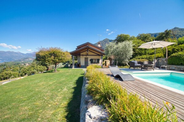 A house with a swimming pool, a deck, and a view of the mountains.
