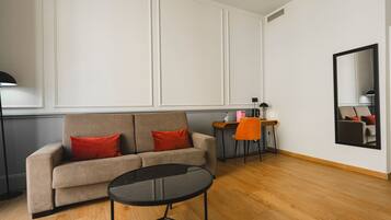 A modern living room with a sofa, a small round table, and a desk with a chair.