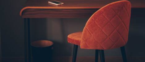 A wooden table with a smartphone on it, a red upholstered chair, and a small round stool.