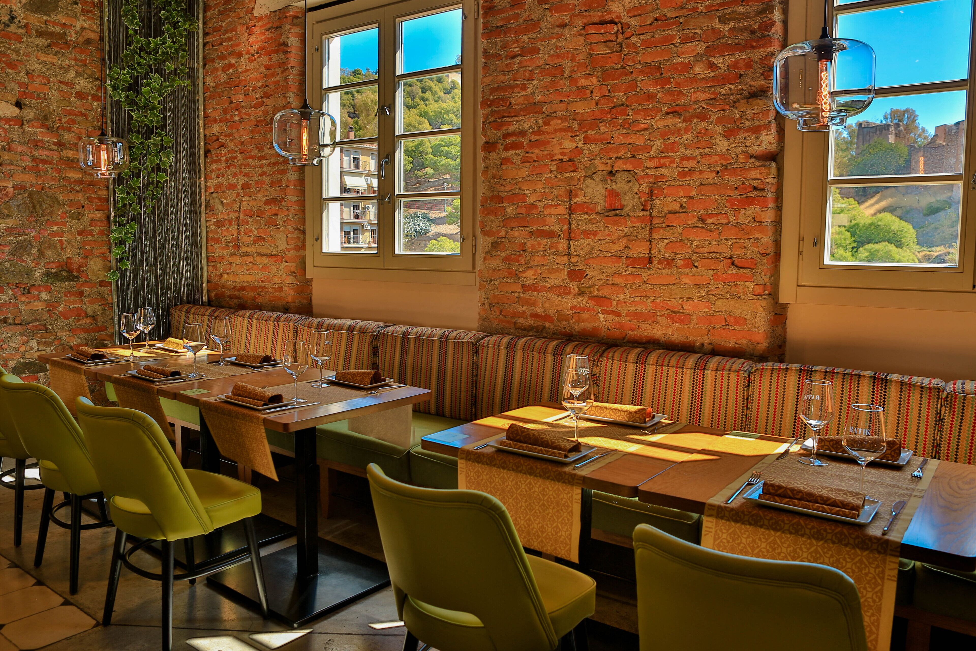 A dining area with a brick wall, a large window, and a bench.