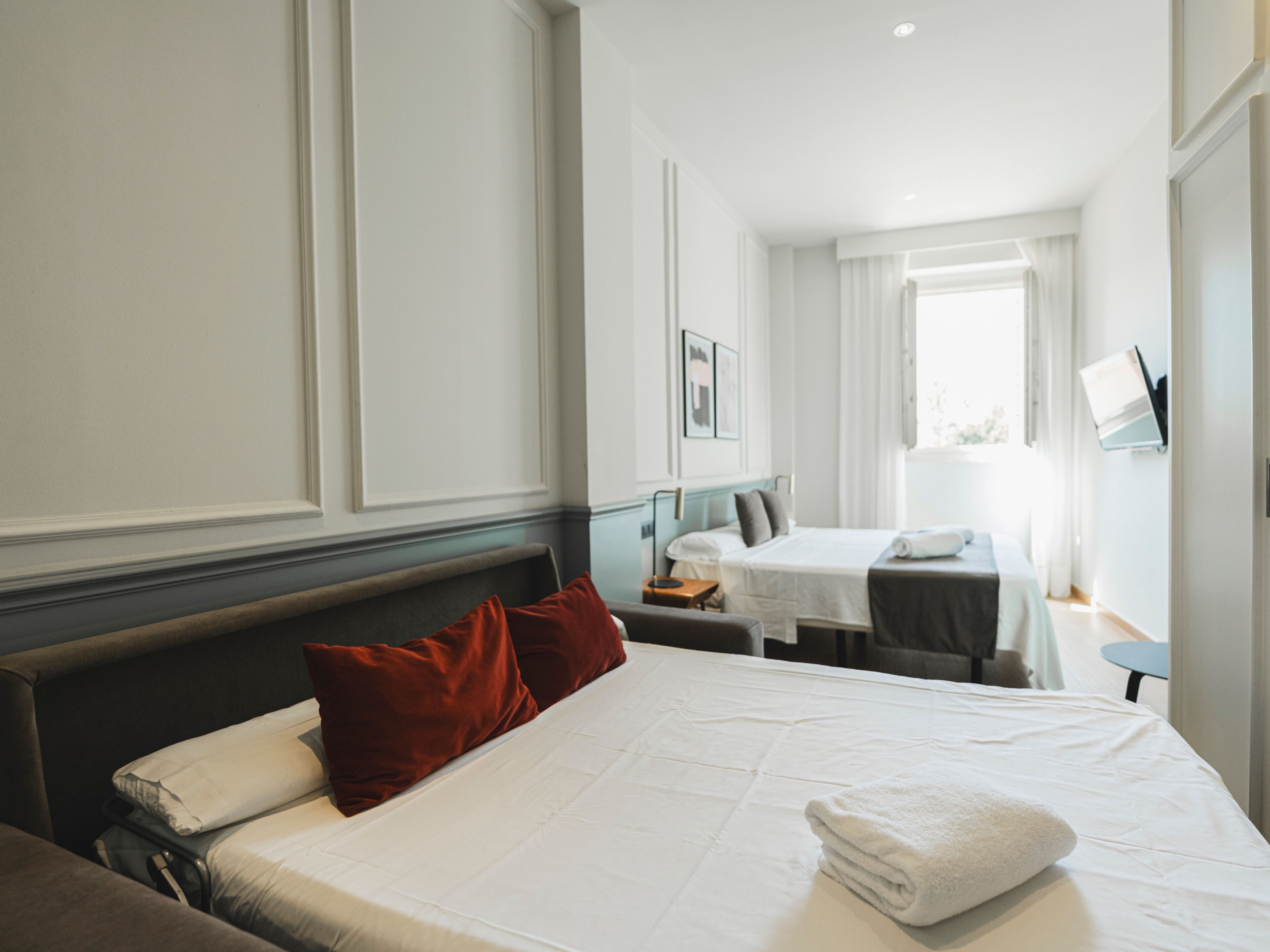 A hotel room with a large bed, a desk, and a chair.