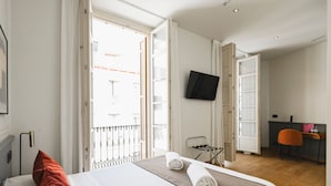 Habitación de hotel con cama, televisión, escritorio y vistas al exterior.