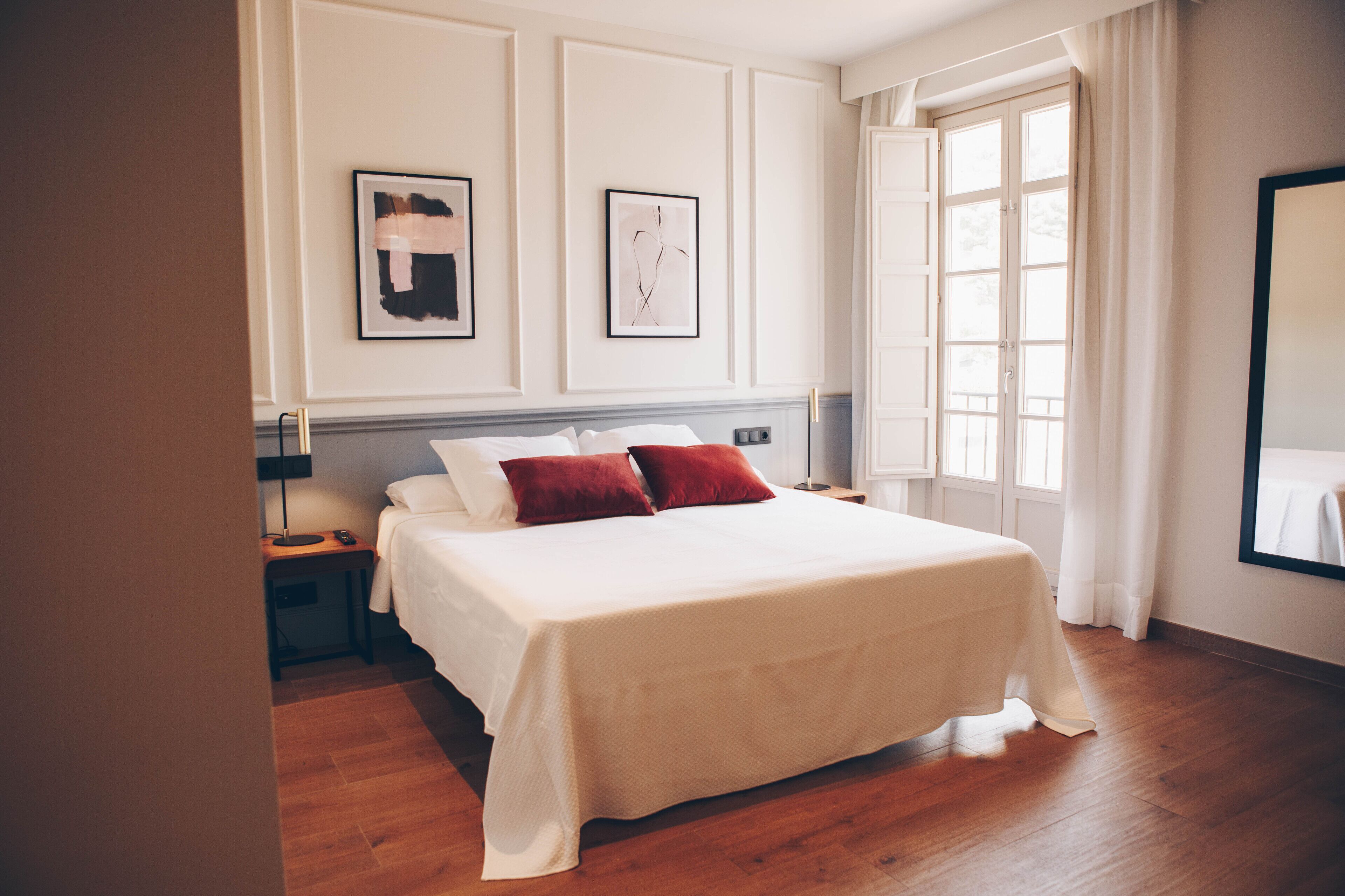 A neatly arranged bedroom with a large bed, two bedside tables, and a window with curtains.