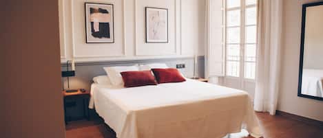A neatly arranged bedroom with a large bed, two bedside tables, and a window with curtains.