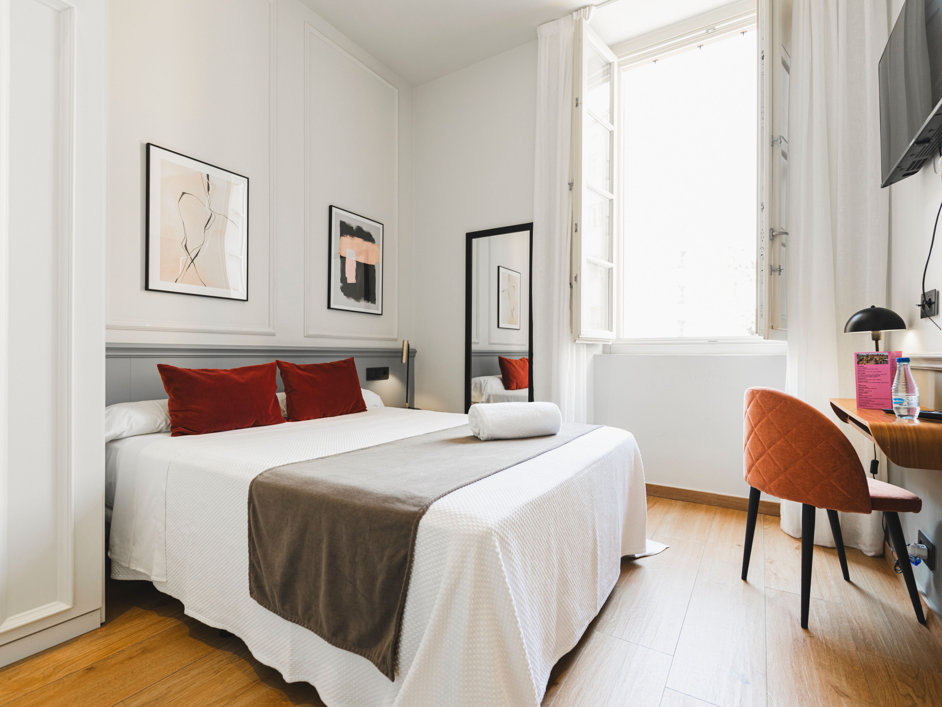 A hotel room with a bed, a desk, and a chair.