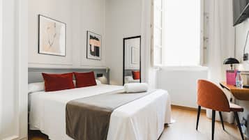 A hotel room with a bed, a desk, and a chair.