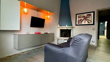 Un salon moderne avec un canapé gris, un téléviseur fixé au mur, une cheminée et un tableau abstrait encadré accroché au mur.