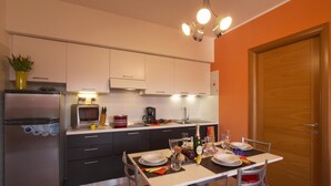 Une cuisine compacte équipée d’un réfrigérateur, d’un four à micro-ondes et d’une table à manger pour quatre personnes.