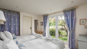 A bedroom with two beds, a mirror, a desk, and a window with curtains.