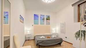 A bedroom with a bed, bedside tables, a chair, and artwork on the wall. - Berny Salo: Near the Lake & Garage (Salò)