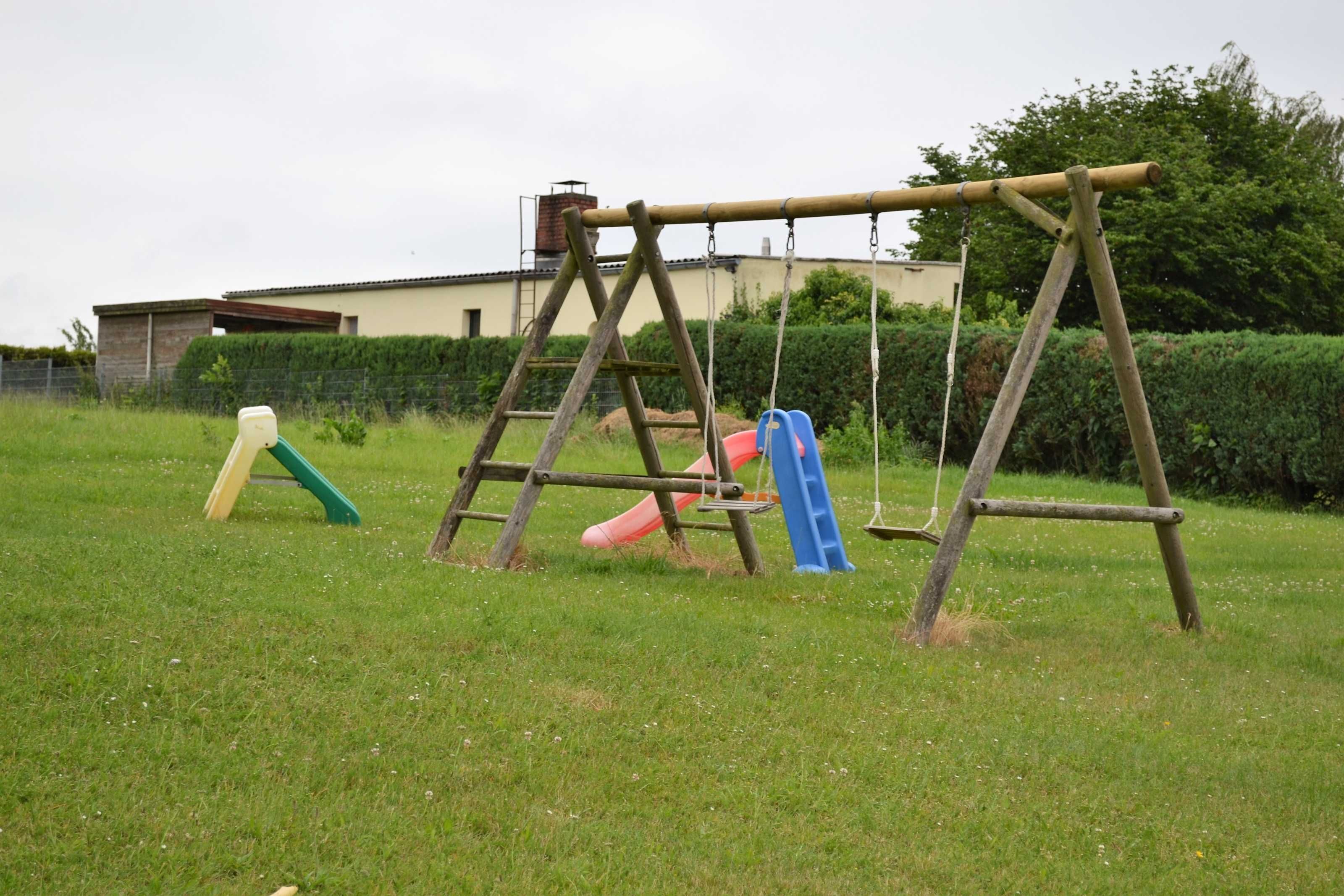 Un parque infantil con columpios y toboganes en un área verde.