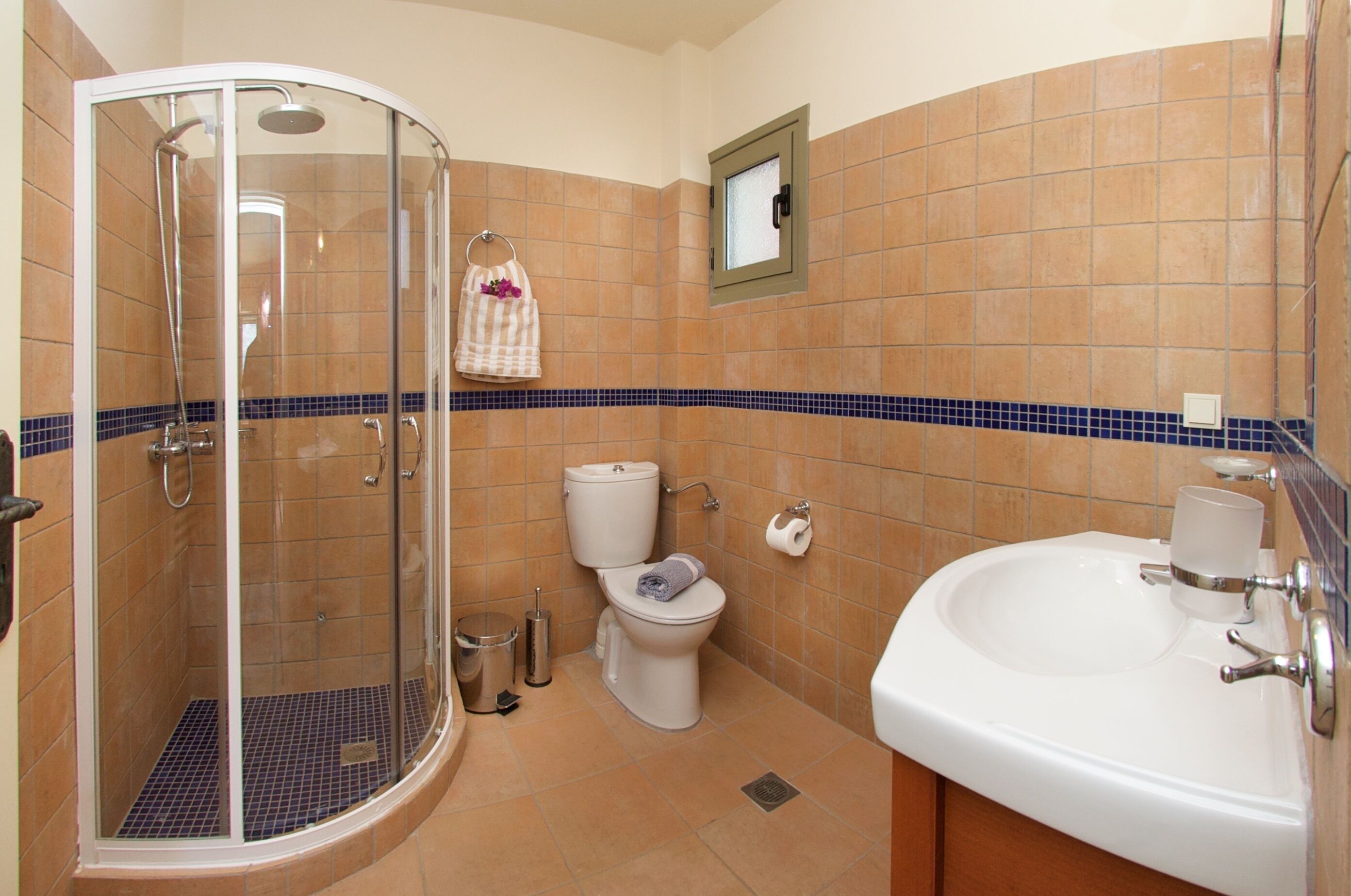 A bathroom with a glass-enclosed shower, a toilet, and a sink.