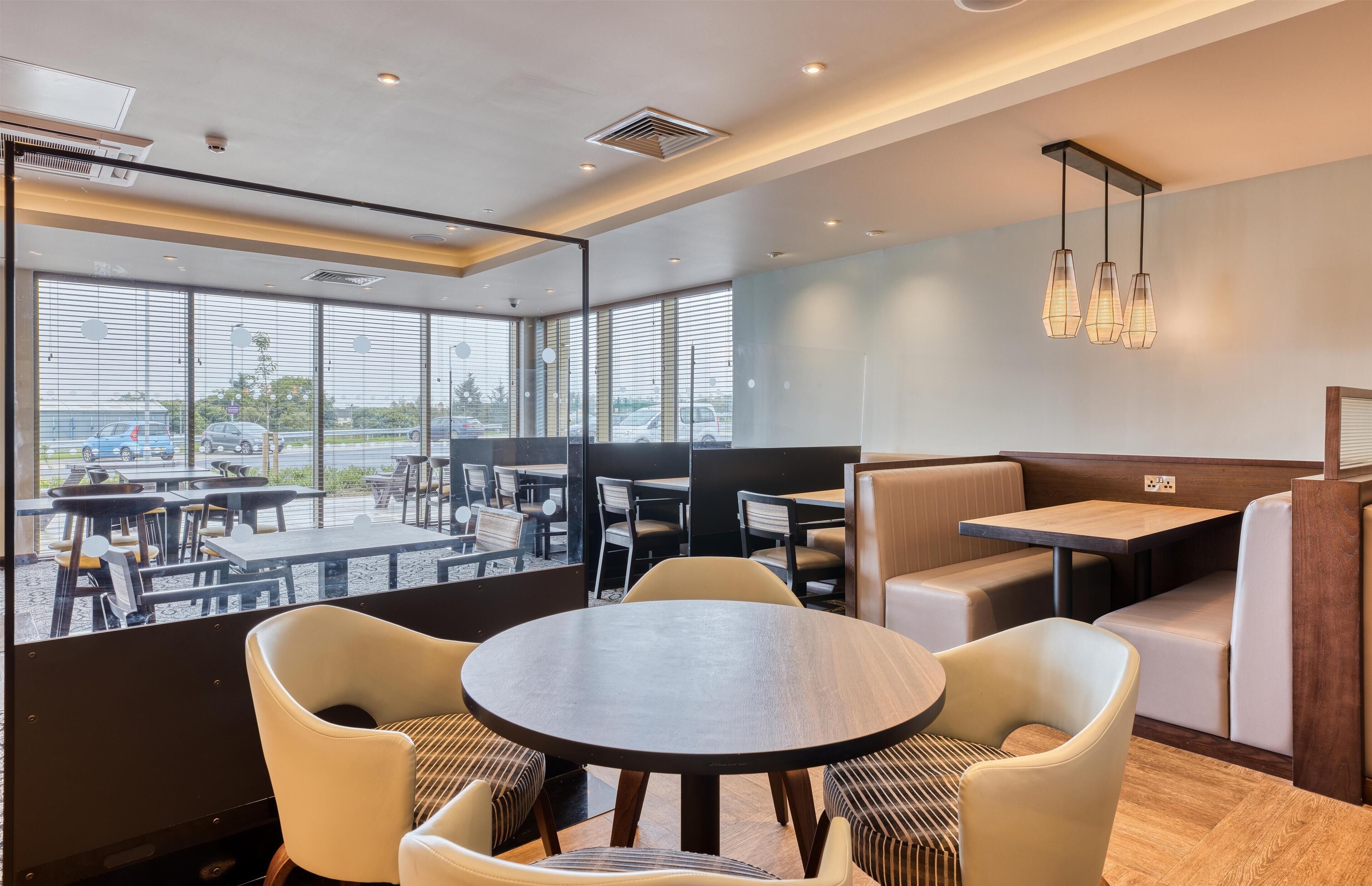 Un restaurant moderne avec des tables rondes, des banquettes confortables et de grandes fenêtres donnant sur le parking.