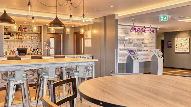 Un espace bar doté d’un long comptoir, de tabourets et de luminaires suspendus.