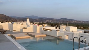 Piscina no terraço com vista para montanhas distantes e uma cidade.