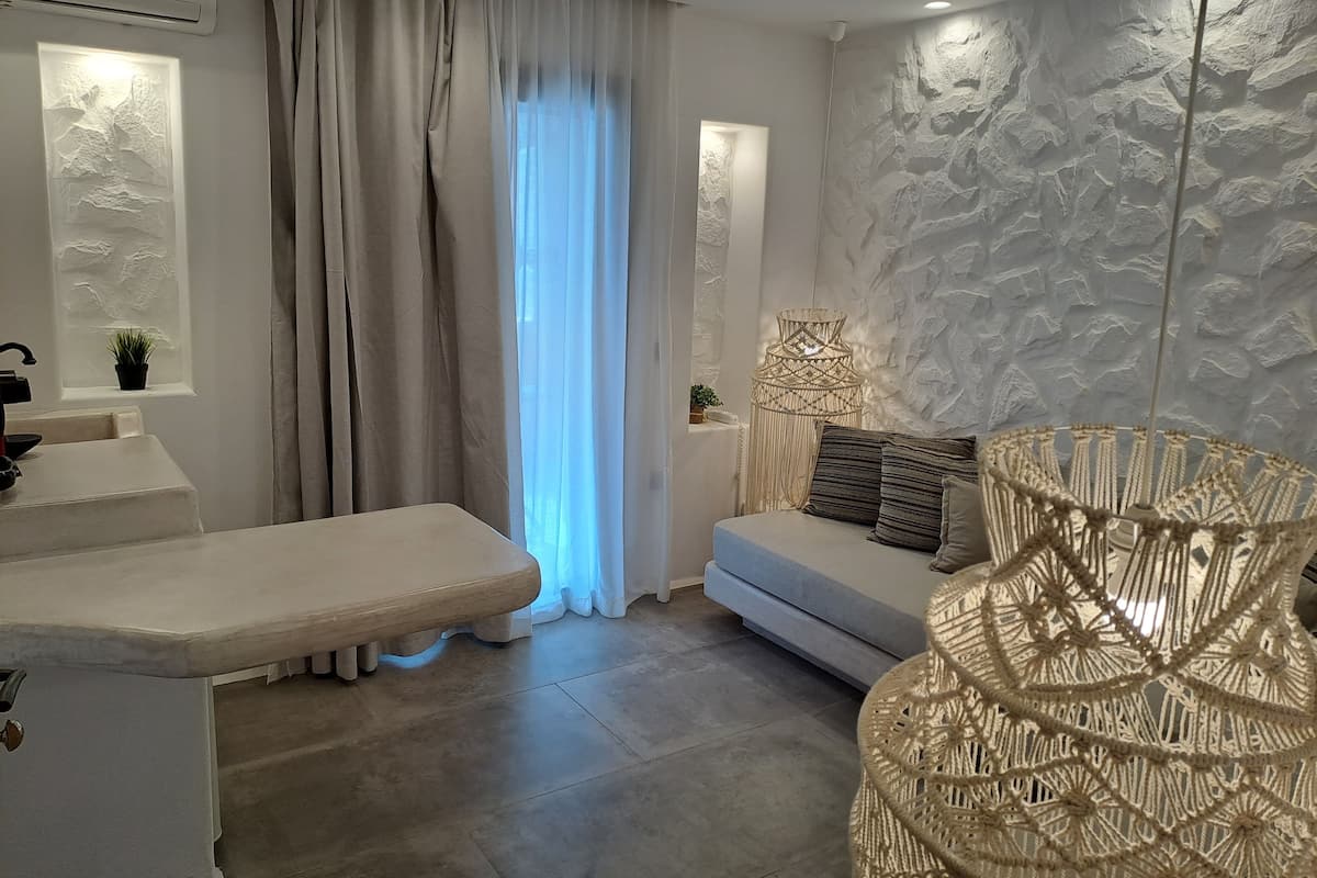 Un salon moderne avec un canapé, un banc, un fauteuil en osier et un mur à texture.