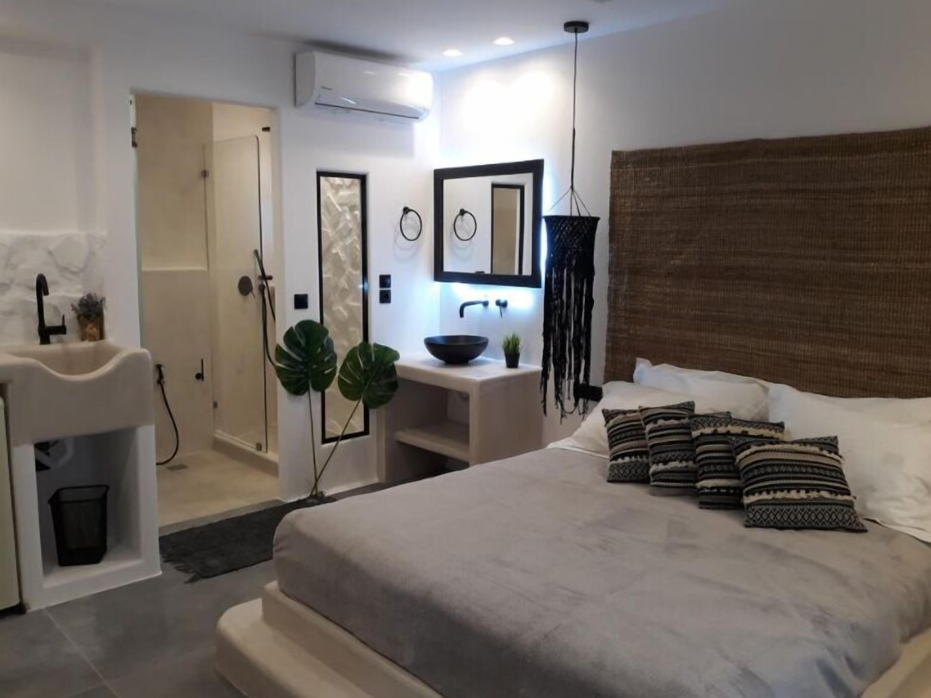 Un dormitorio moderno con cama, mesita de noche y baño con ducha y lavamanos.