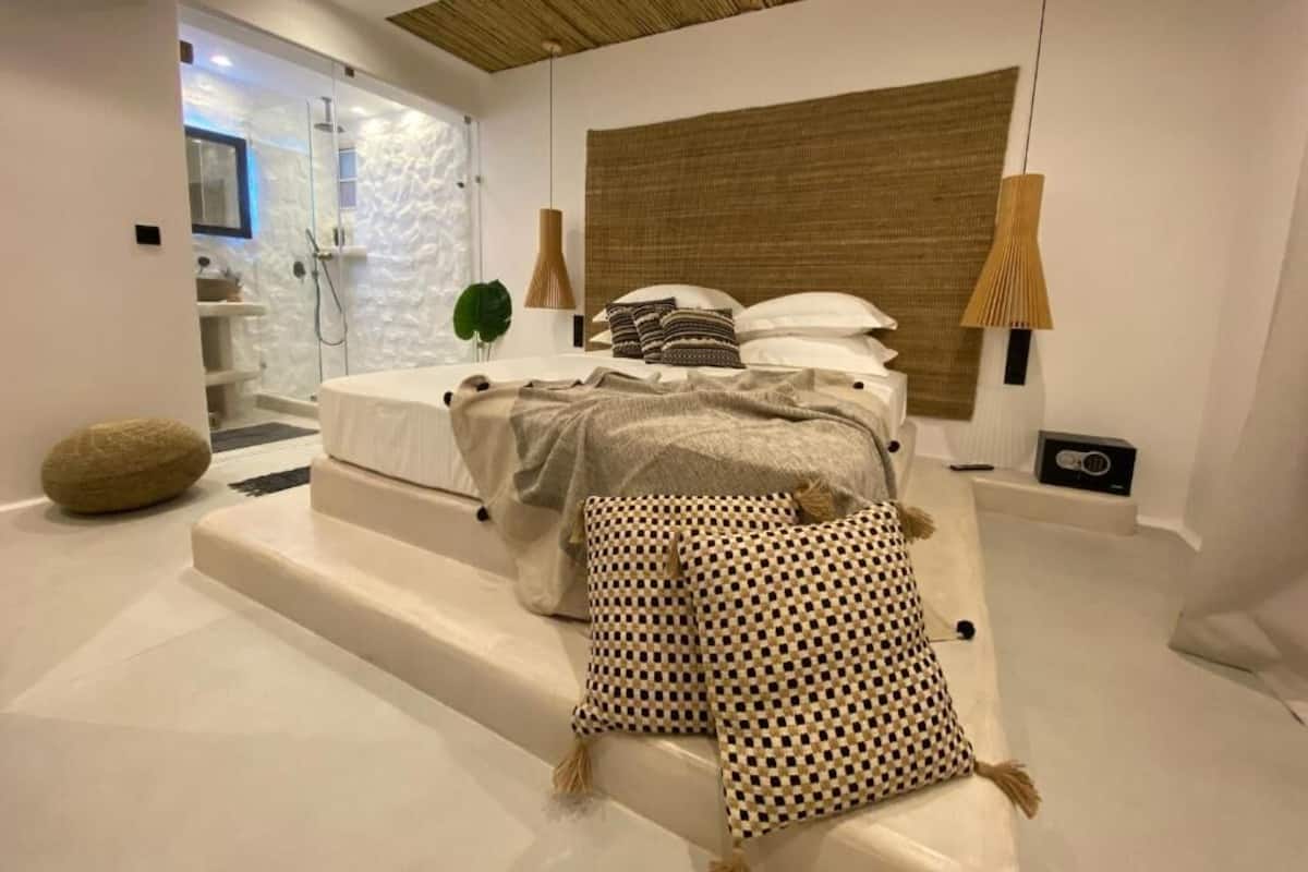 Une chambre moderne comprenant un lit, une table de chevet, une lampe et un espace douche.