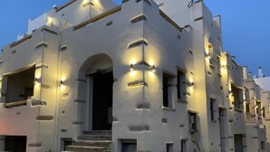 Um edifício moderno com design arquitetônico único, apresentando uma entrada em arco central e várias janelas.