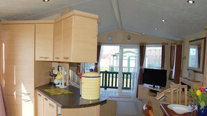 Una cocina compacta con muebles de madera, una isla central y un televisor.