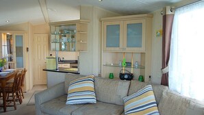 Un espacio habitable compacto con kitchenette, comedor y sofá con cojines a rayas.