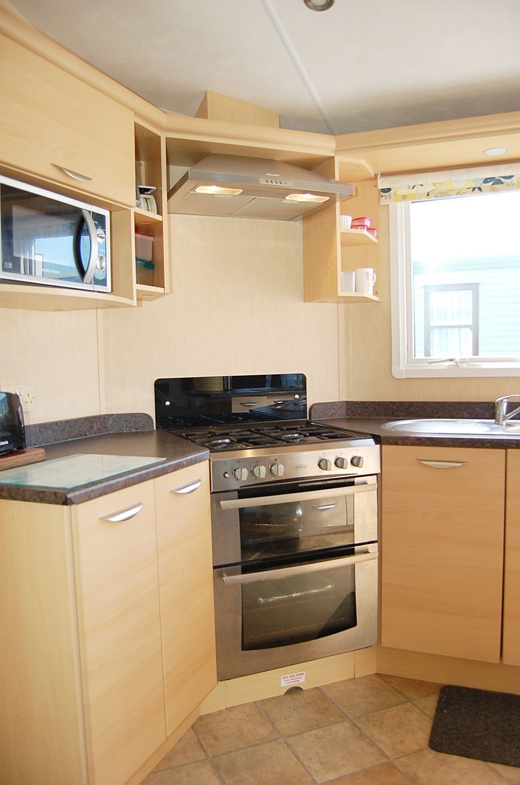 Cocina compacta con estufa, horno, microondas y armarios de madera.