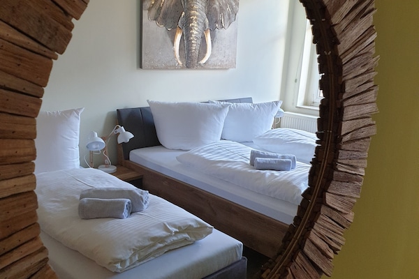 helles Schlafzimmer mit einem großen Doppelbett und einem Extrabett