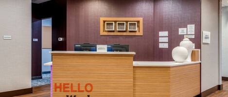 A reception desk with a sign reading "HELLO Waukegan" and a Lenovo computer on it.